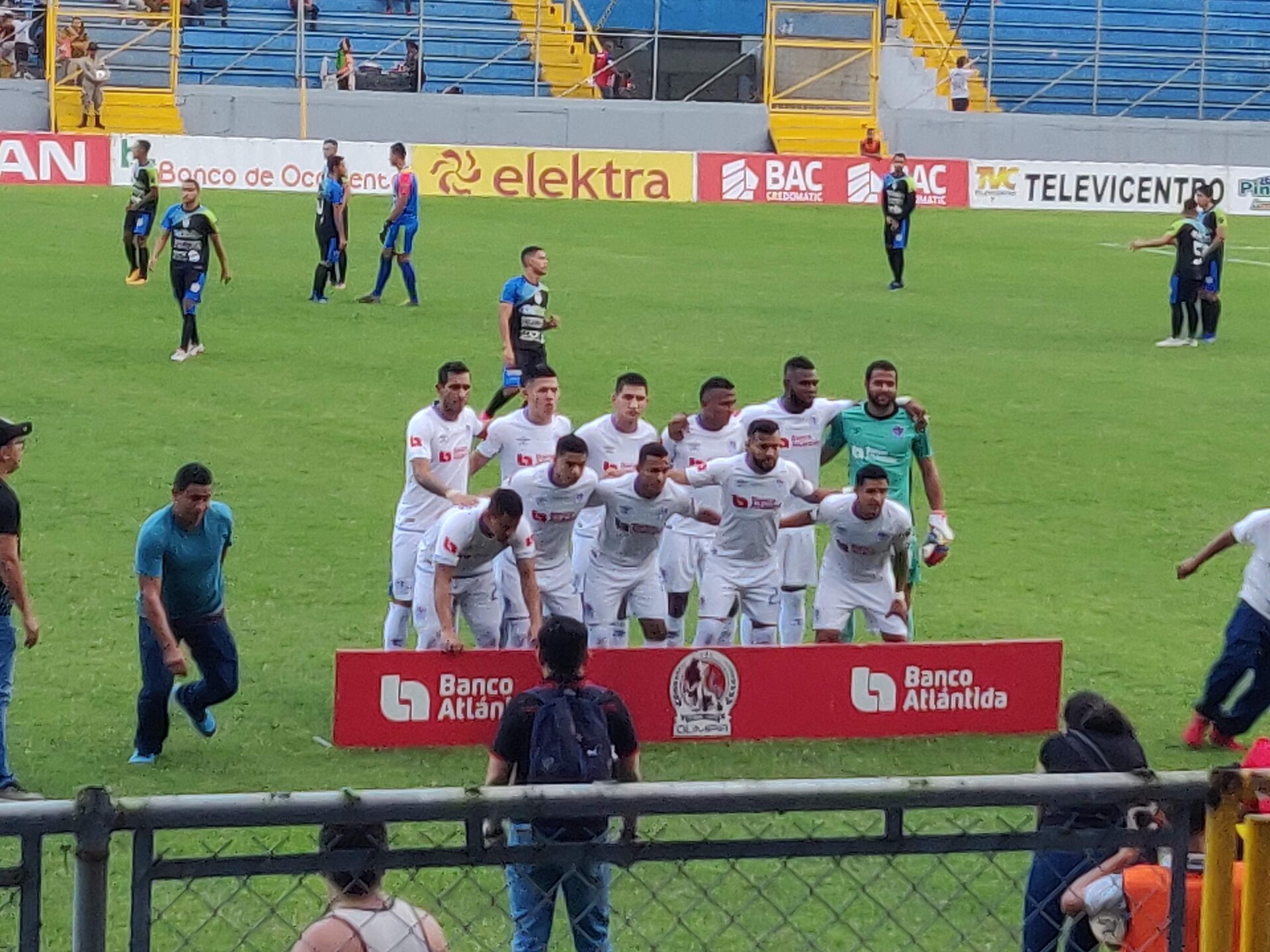 Olimpia players in white gather on the pitch for a team photo before a league match in Honduras