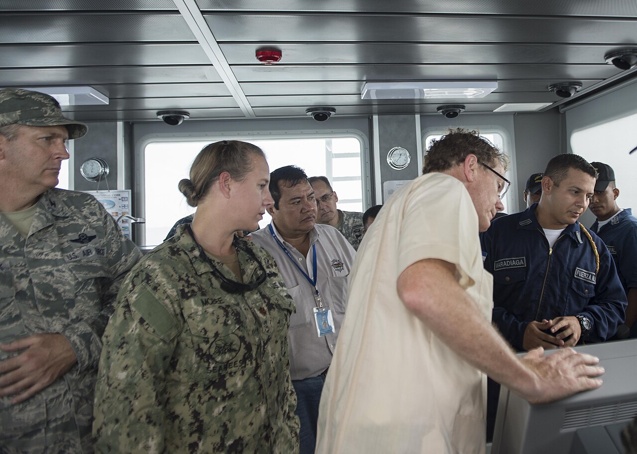 US and Honduran military officers and officials gather on the bridge of a Honduran navy patrol boat