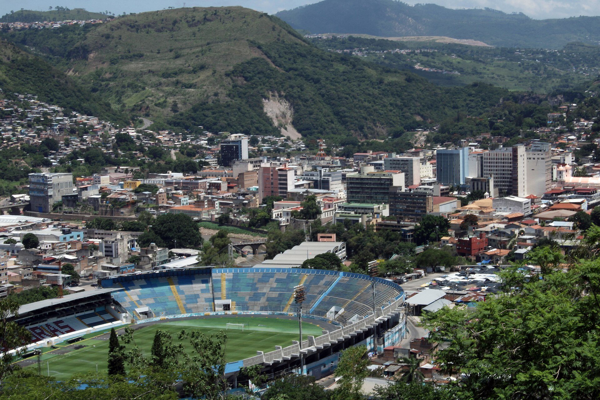 View over the historic centre of Tegucigalpa and Comayagüela with a football stadium in the foreground and green hills behind