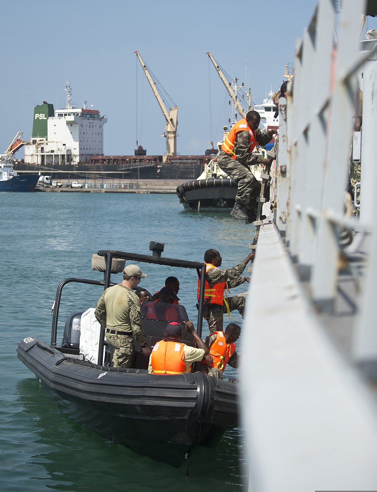 Djiboutian marines climb from a boat onto a ship during an exercise at the Port of Djibouti