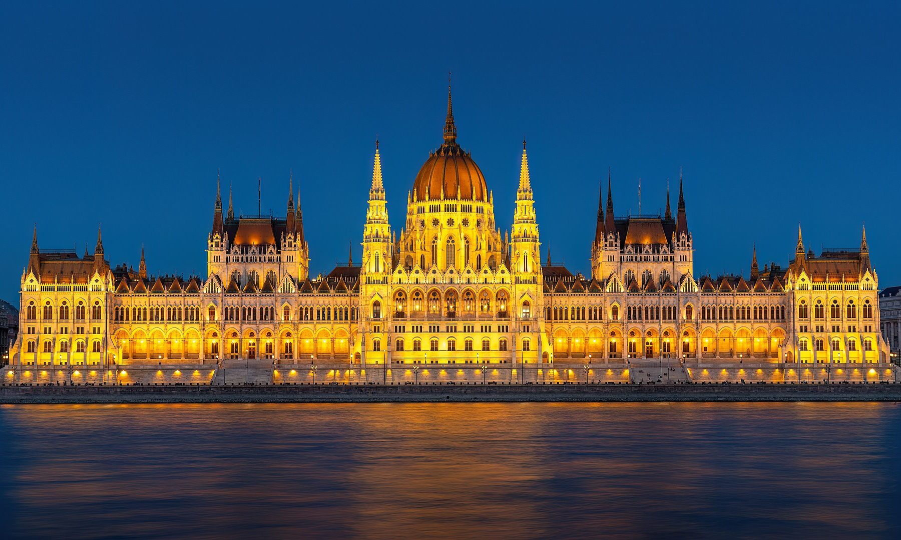 The Hungarian Parliament Building in Budapest lit up at night beside the Danube