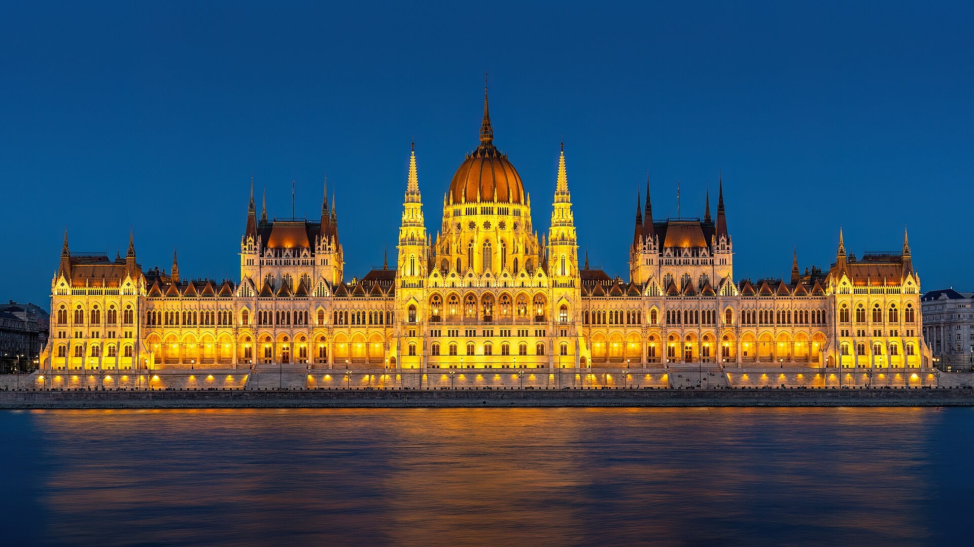The Hungarian Parliament Building in Budapest lit up at night beside the Danube