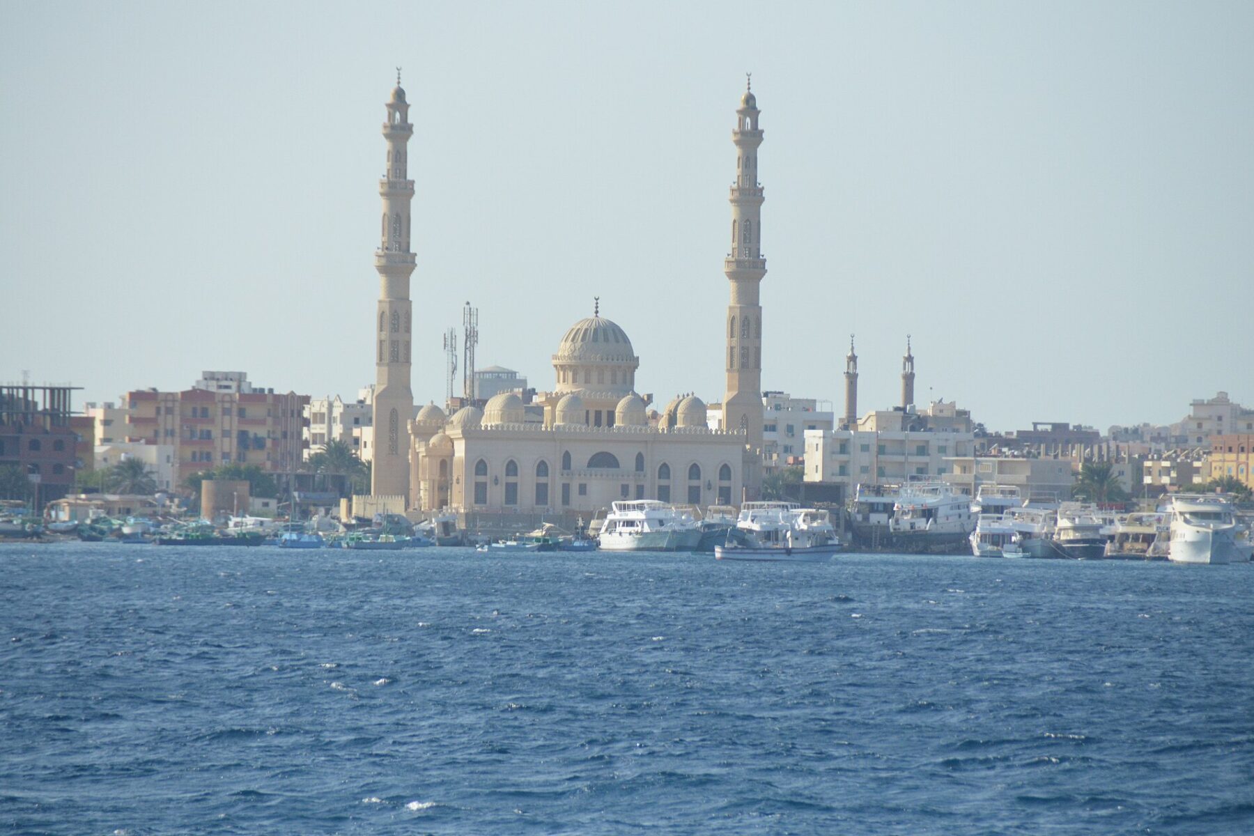 Al-Mina Mosque with its two minarets above the harbour of Hurghada, Egypt, with dive and tour boats moored on the Red Sea