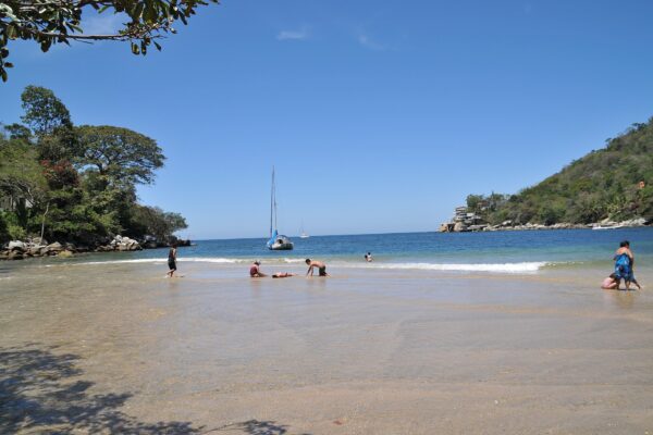 Calm bay with a moored sailboat and bathers at Boca de Tomatlán on the Pacific coast of Jalisco, Mexico