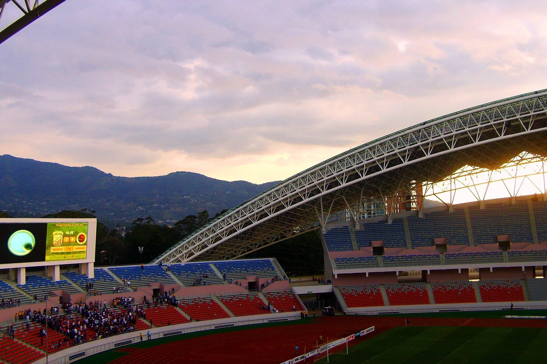 Sunset over the Estadio Nacional in San José, Costa Rica, with its curved steel roof, stands and mountains behind