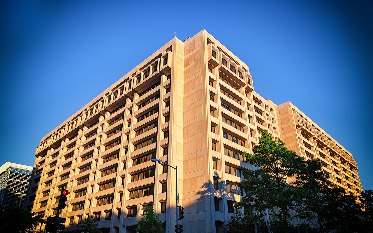 The pale stone headquarters building of the International Monetary Fund at 700 19th Street NW in Washington, lit by evening sun