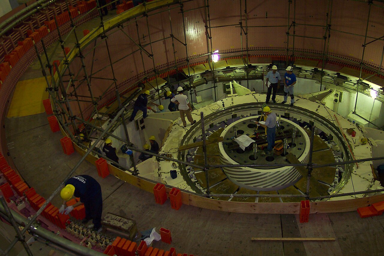 Technicians in hard hats working on scaffolding inside the round chamber of a generating unit