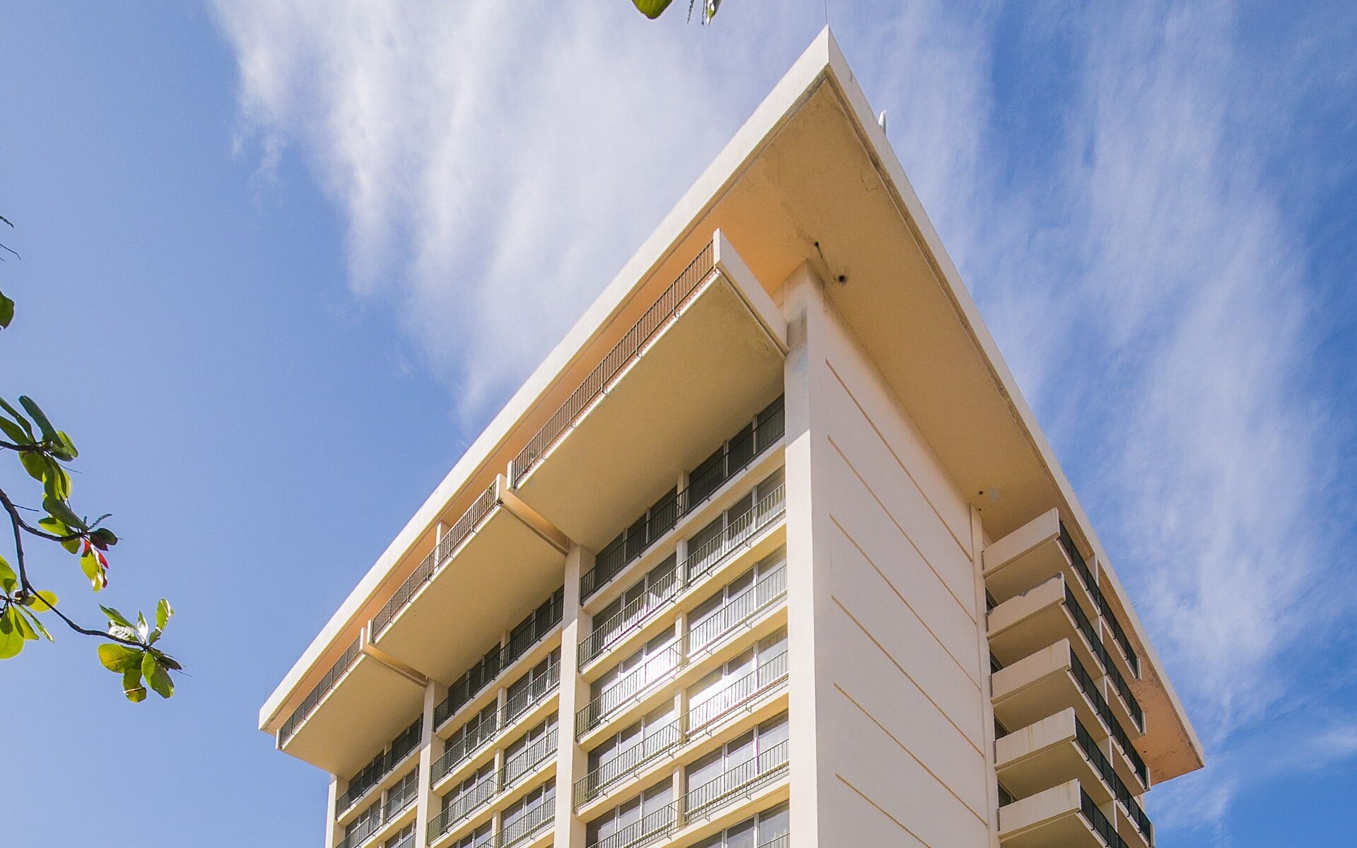 The Courtleigh Hotel and Suites tower in New Kingston, Jamaica, seen from below against a blue sky