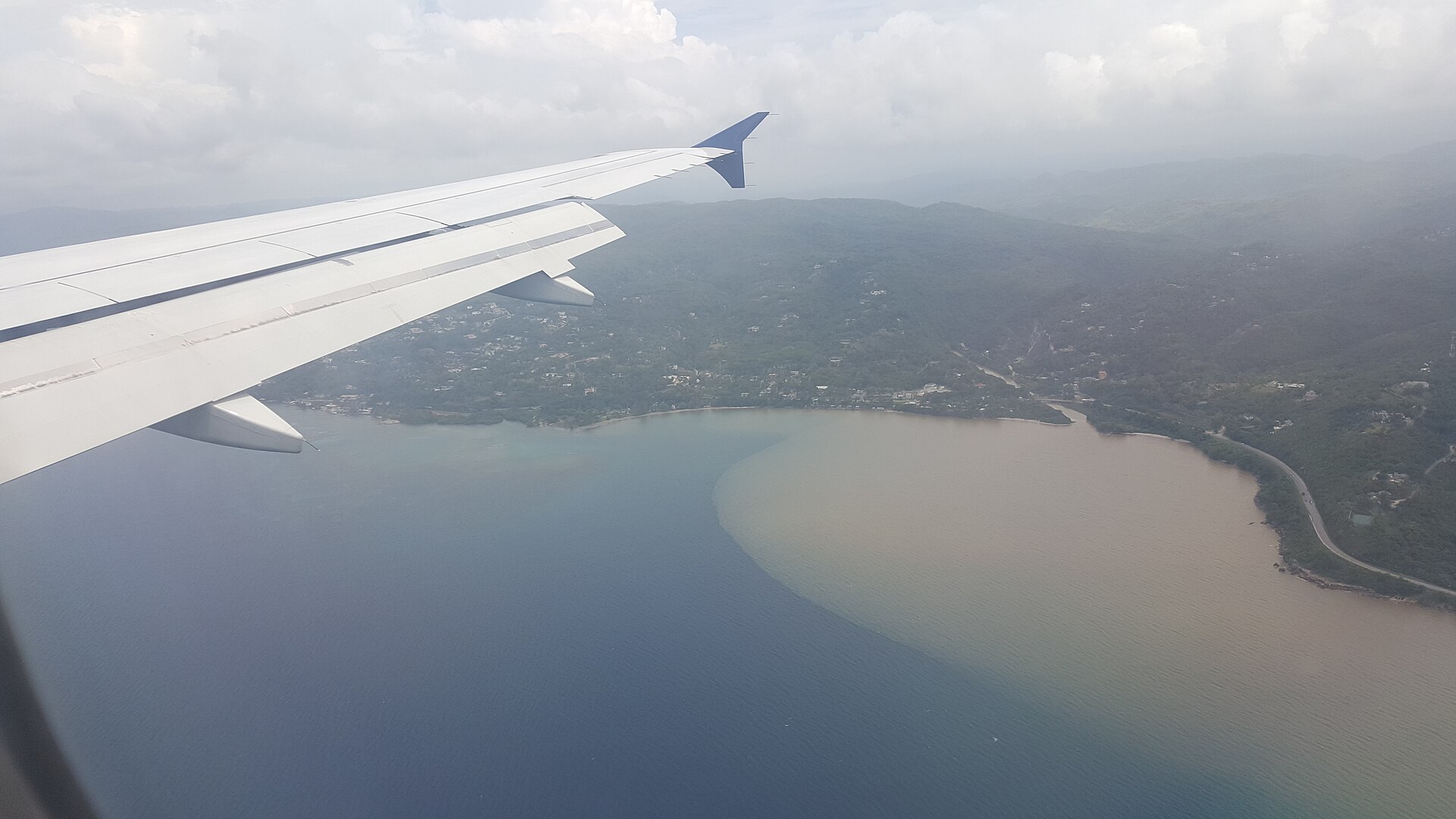 Jamaica continent question: a stretch of Jamaica’s coast and hills seen from an aircraft window