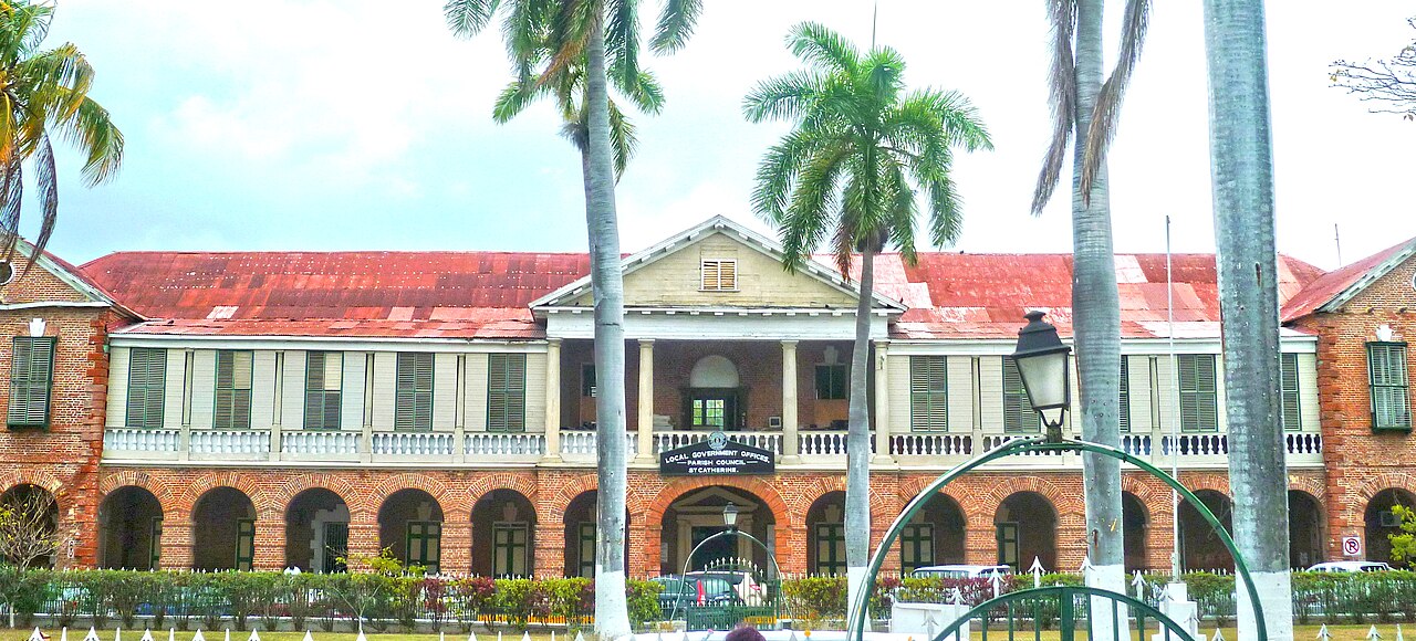 Red-roofed brick and timber parish council building with palm trees in Spanish Town, St Catherine, Jamaica
