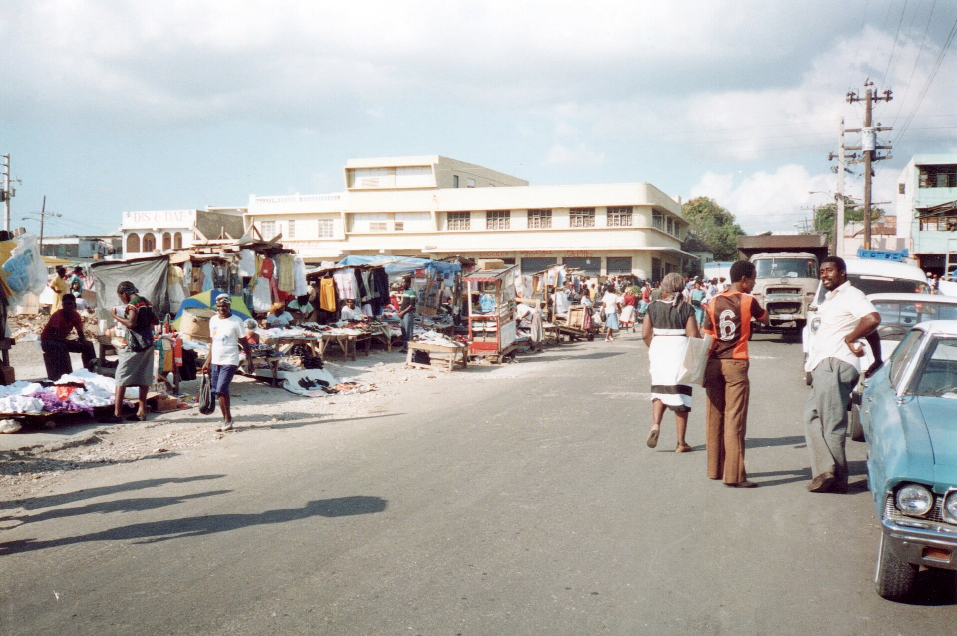 A street in downtown Kingston, Jamaica, with market stalls, pedestrians and parked vehicles