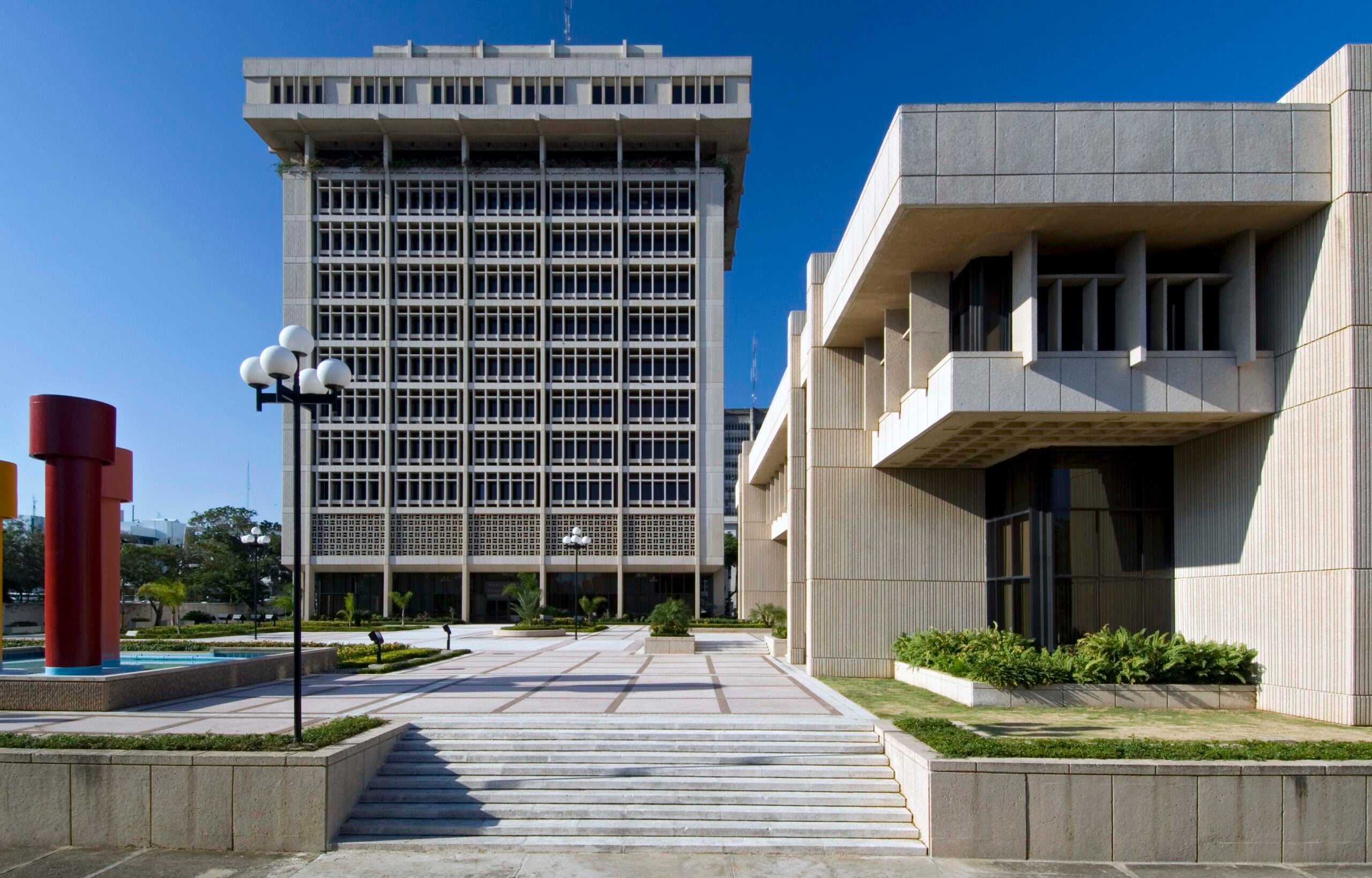 Modernist Central Bank tower and plaza in central Santo Domingo under a clear blue sky.