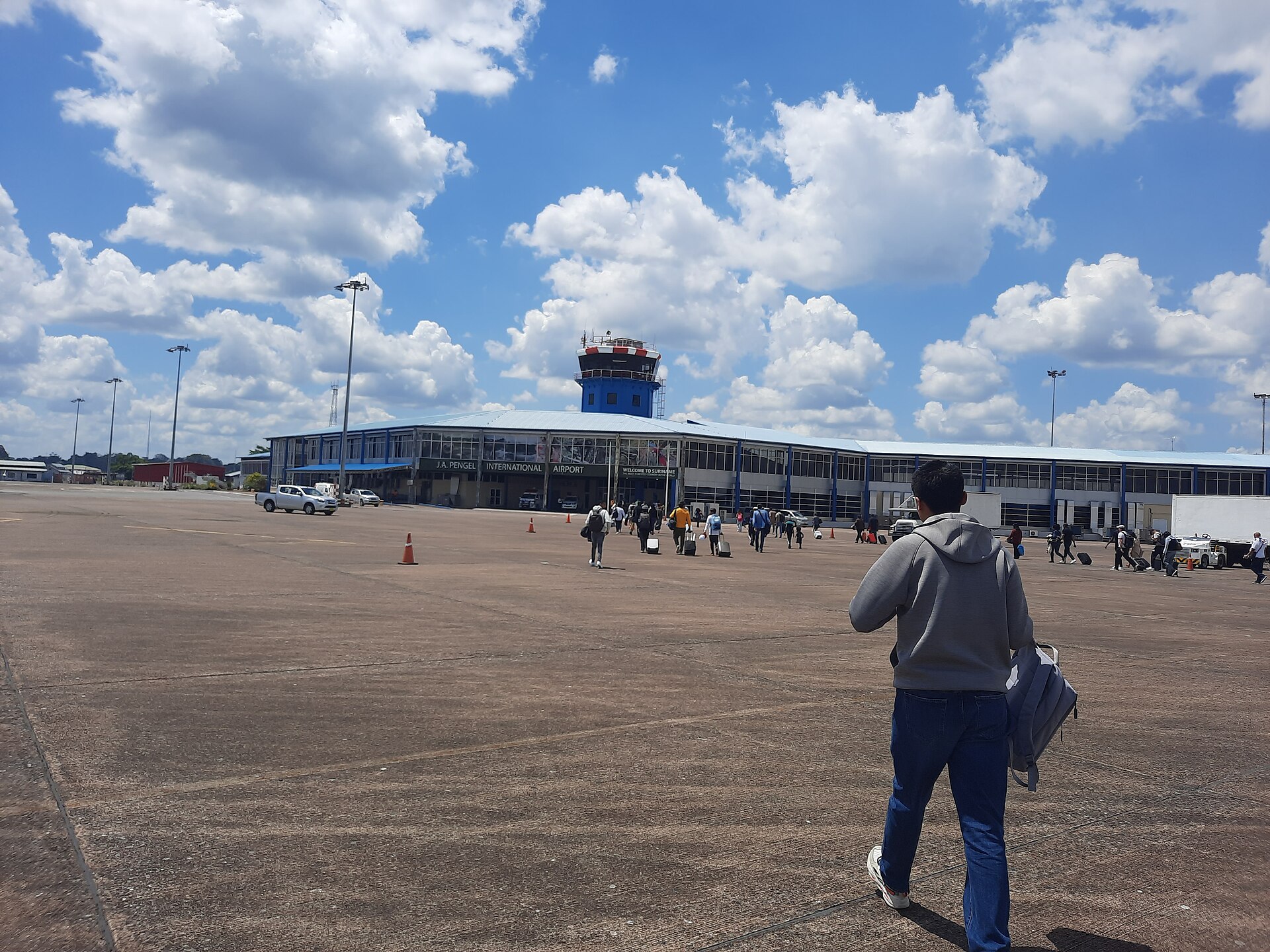 Passengers walking across the apron towards the terminal and control tower of Johan Adolf Pengel International Airport, Suriname