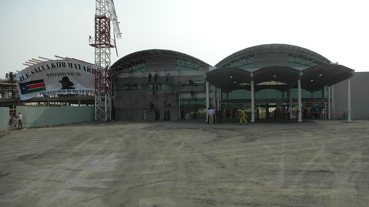 Front of the new passenger terminal at Juba Airport, South Sudan, under construction in 2011, with scaffolding, a crane and a welcome banner.