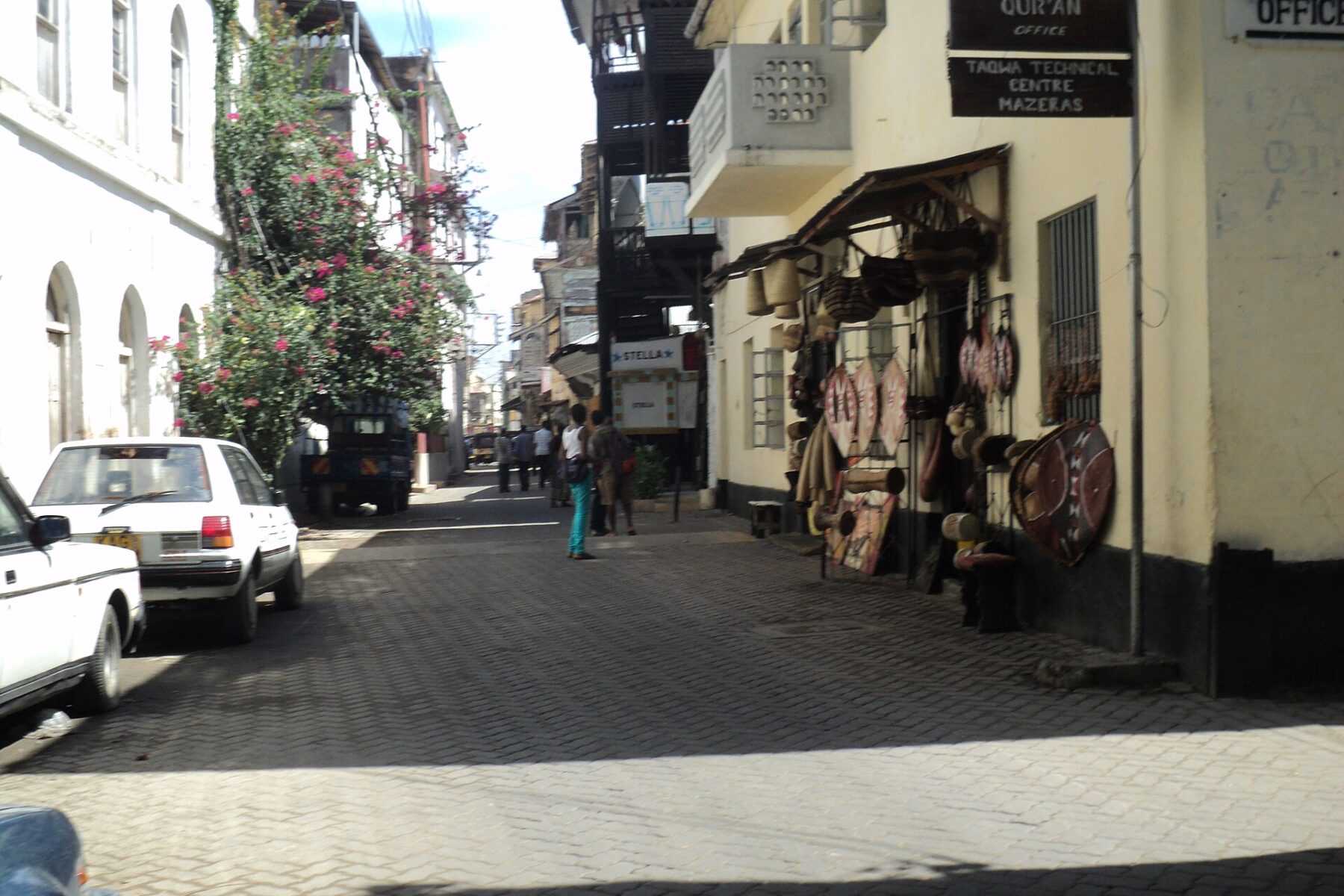 A street in Mombasa Old Town, Kenya, with shops and parked cars