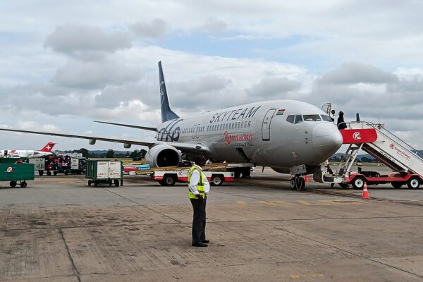 A grey Kenya Airways Boeing 737 in SkyTeam livery on the apron with boarding stairs