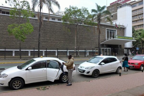 The Nairobi City County Assembly building behind taxis parked on a city street in Nairobi