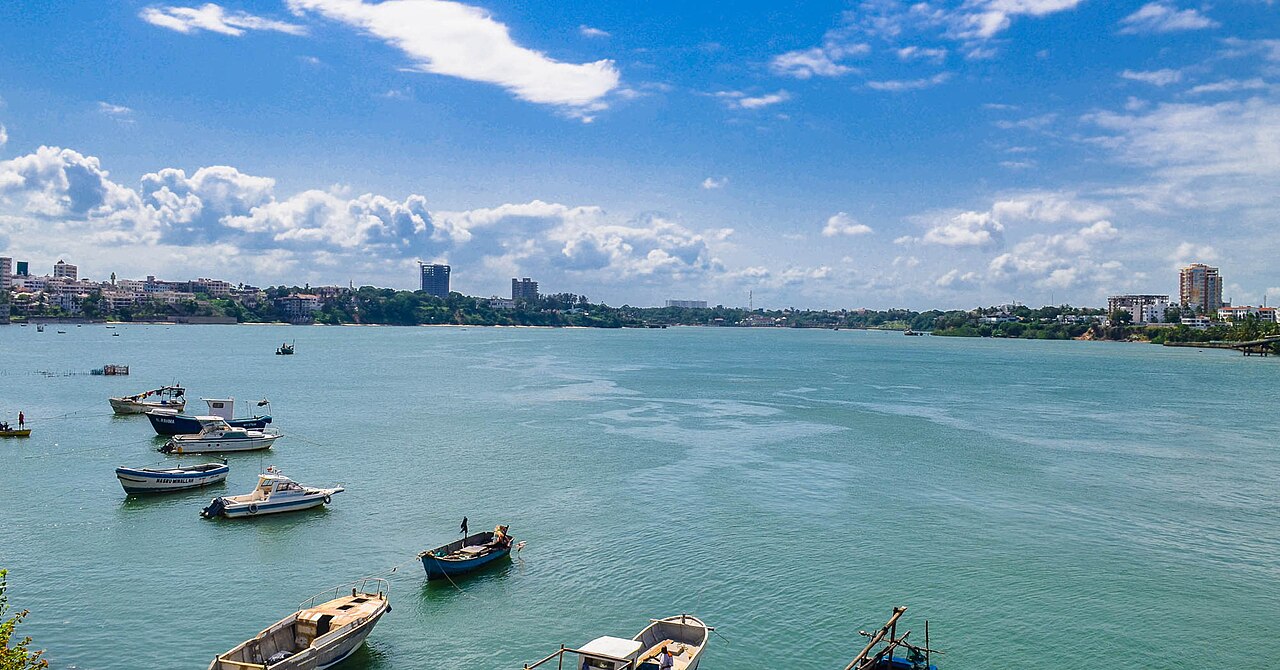 Small boats moored on blue water off Mombasa with the city skyline behind
