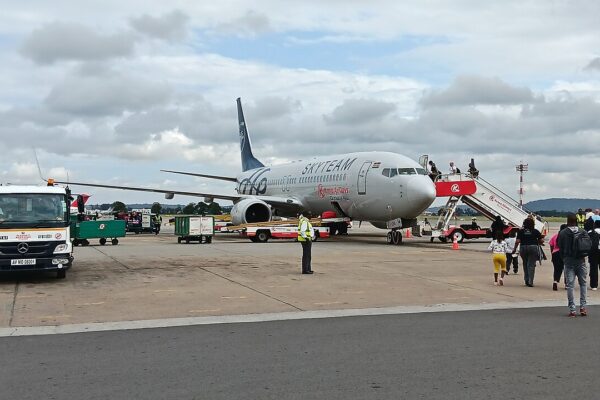 Travellers walk across the apron to board a Kenya Airways Boeing 737 in SkyTeam livery at Mombasa airport