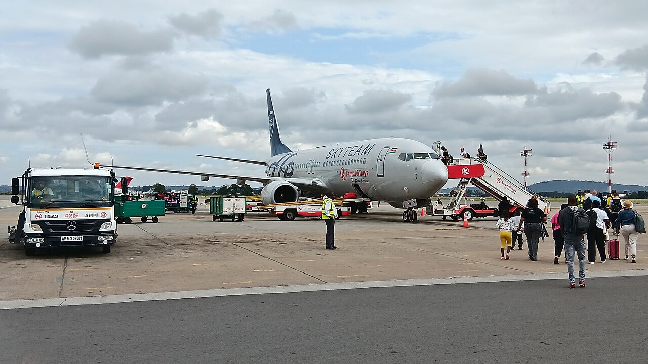 Travellers walk across the apron to board a Kenya Airways Boeing 737 in SkyTeam livery at Mombasa airport