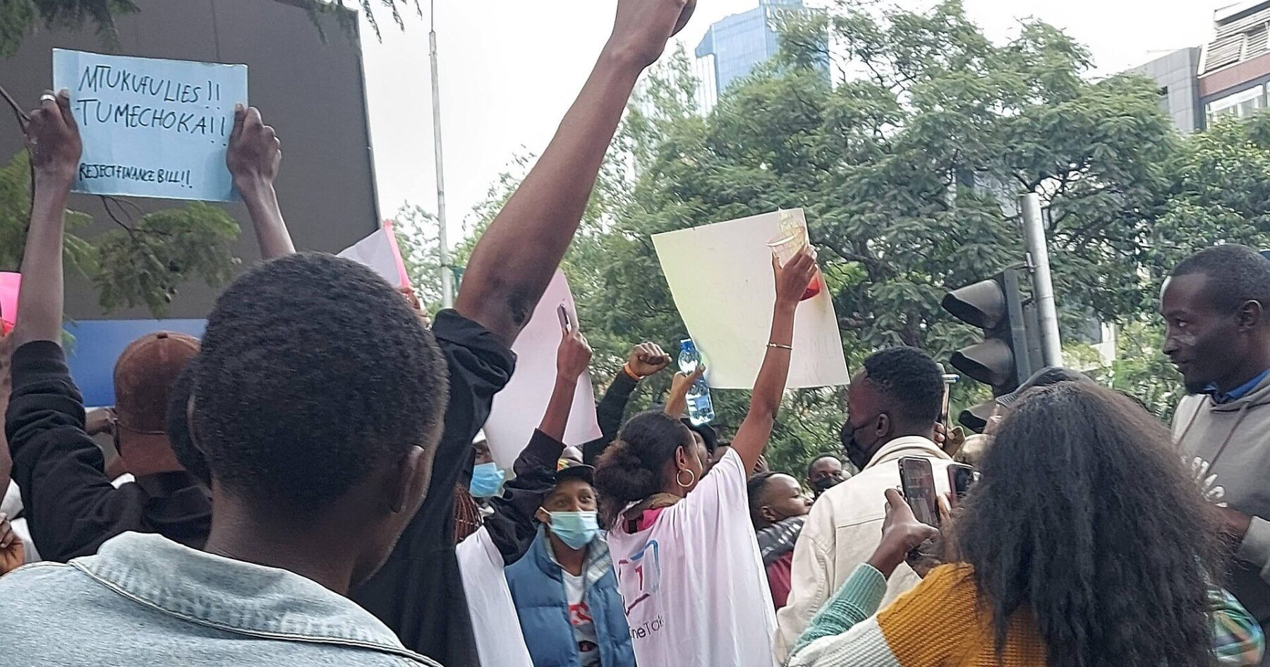 Protesters raise their fists and hold signs against the Finance Bill on a Nairobi street in June 2024