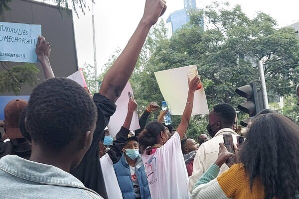 Protesters raise their fists and hold signs against the Finance Bill on a Nairobi street in June 2024