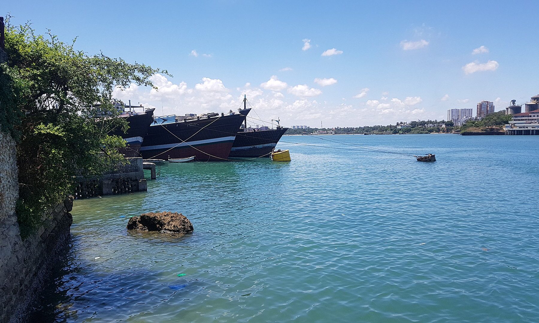 Wooden vessels moored at the old town import dock in Mombasa, Kenya, under a blue sky