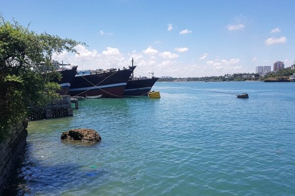 Wooden vessels moored at the old town import dock in Mombasa, Kenya, under a blue sky