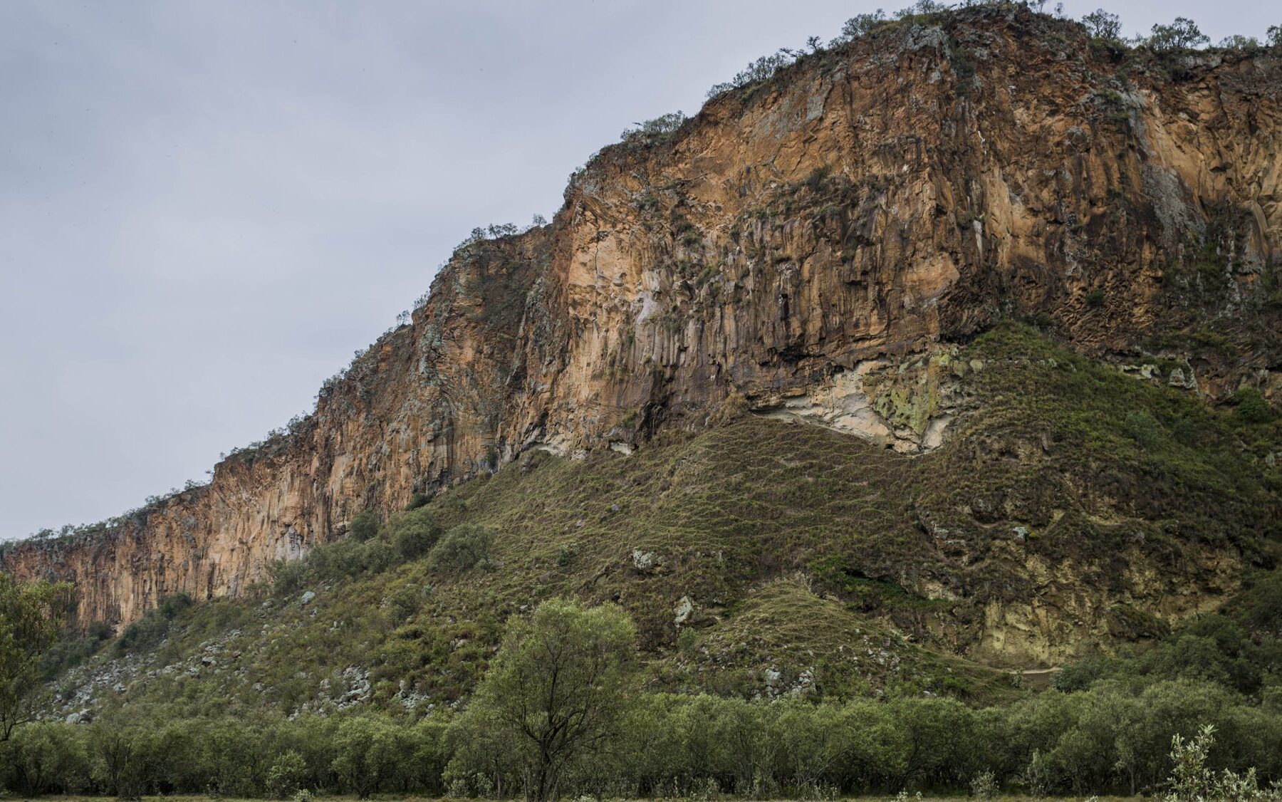 Volcanic cliffs above green bush in Hell's Gate National Park near Naivasha, Kenya, beside the Olkaria geothermal field