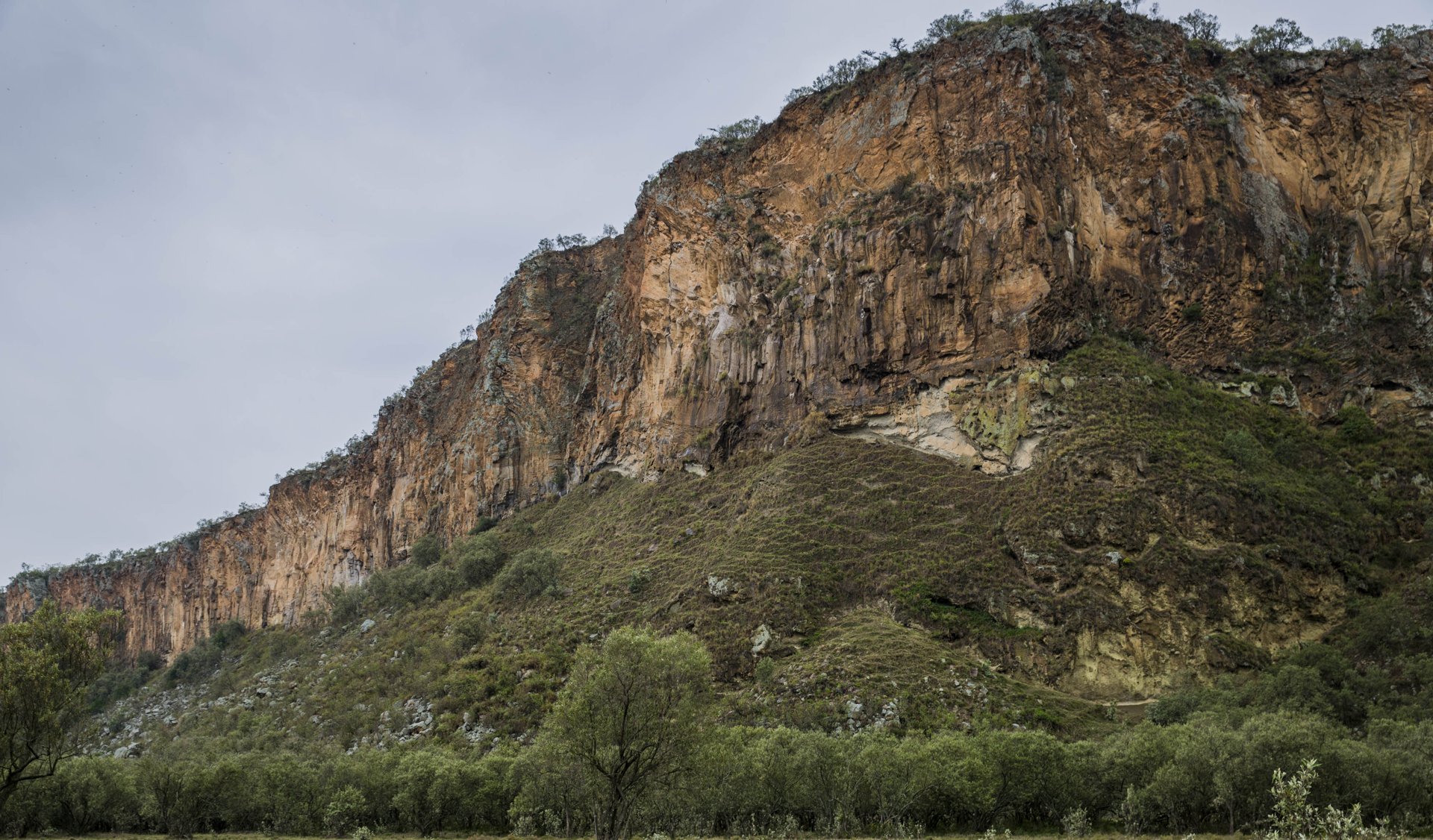 Volcanic cliffs above green bush in Hell's Gate National Park near Naivasha, Kenya, beside the Olkaria geothermal field