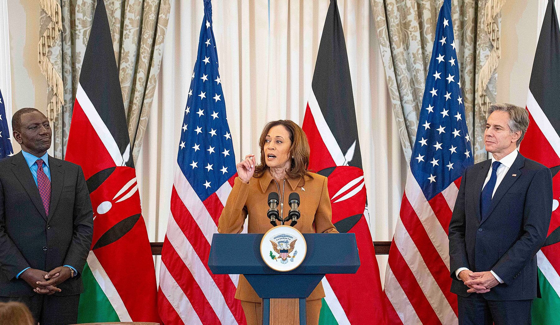 Kenyan President William Ruto at left and US Secretary of State Antony Blinken at right stand either side of US Vice President Kamala Harris, who speaks at a podium, with Kenyan and US flags behind them