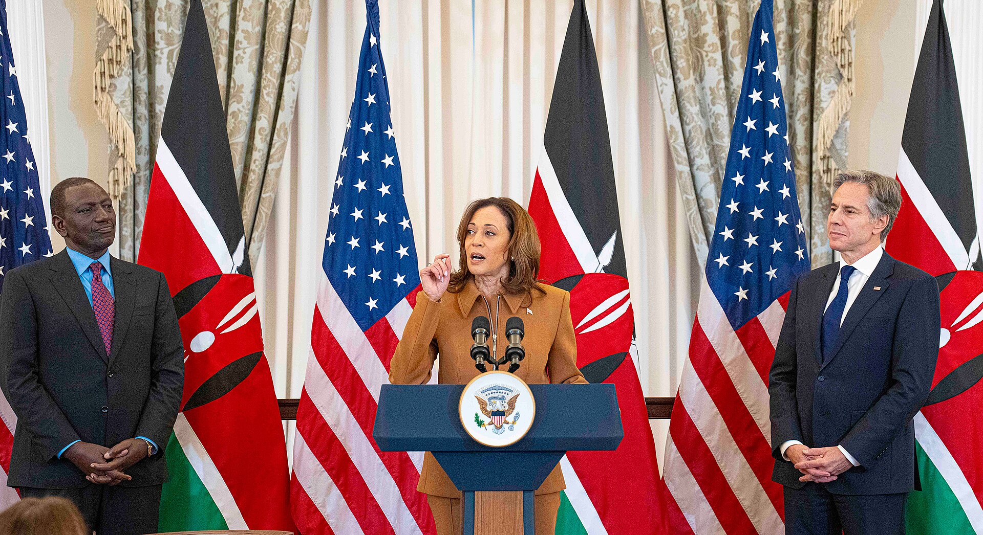 Kenyan President William Ruto at left and US Secretary of State Antony Blinken at right stand either side of US Vice President Kamala Harris, who speaks at a podium, with Kenyan and US flags behind them