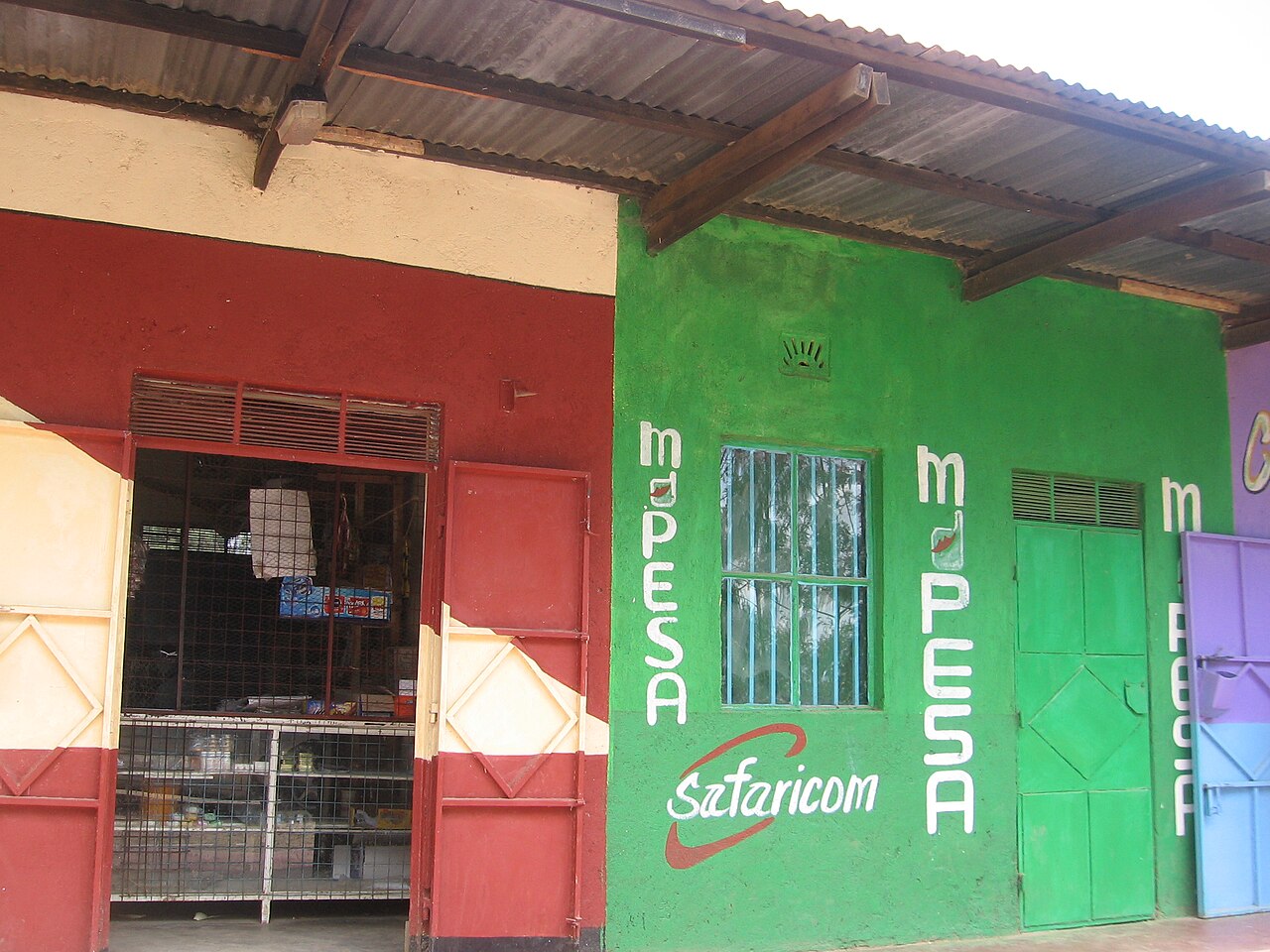 Green-painted Kenyan roadside shop with M-Pesa and Safaricom signs painted on its wall