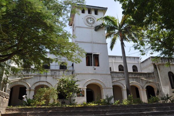 The old colonial-era law courts building in Mombasa, Kenya, with a clock tower, arched arcades and a palm tree