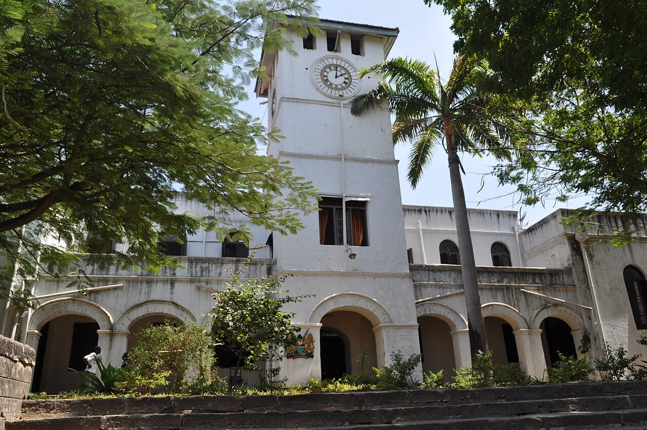 The old colonial-era law courts building in Mombasa, Kenya, with a clock tower, arched arcades and a palm tree