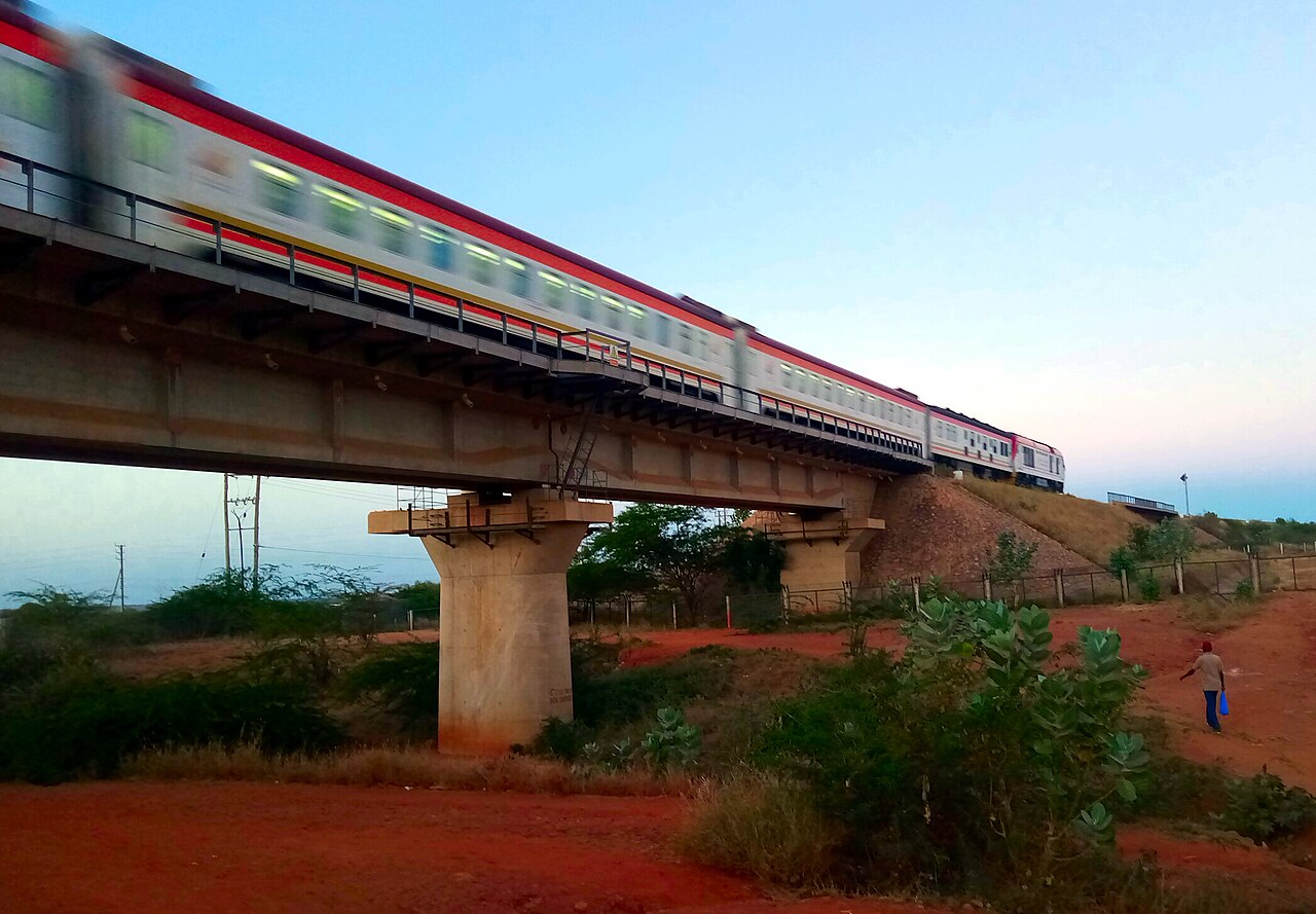 An express passenger train crossing a concrete viaduct on the Mombasa to Nairobi standard gauge railway, with red earth and bush below