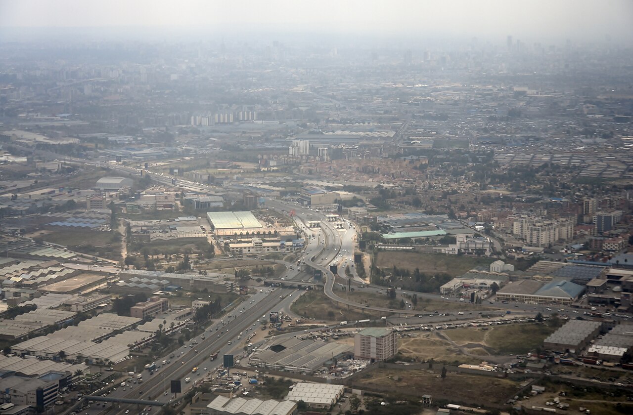 Aerial view of the Nairobi Expressway and surrounding roads, warehouses and housing under hazy skies.