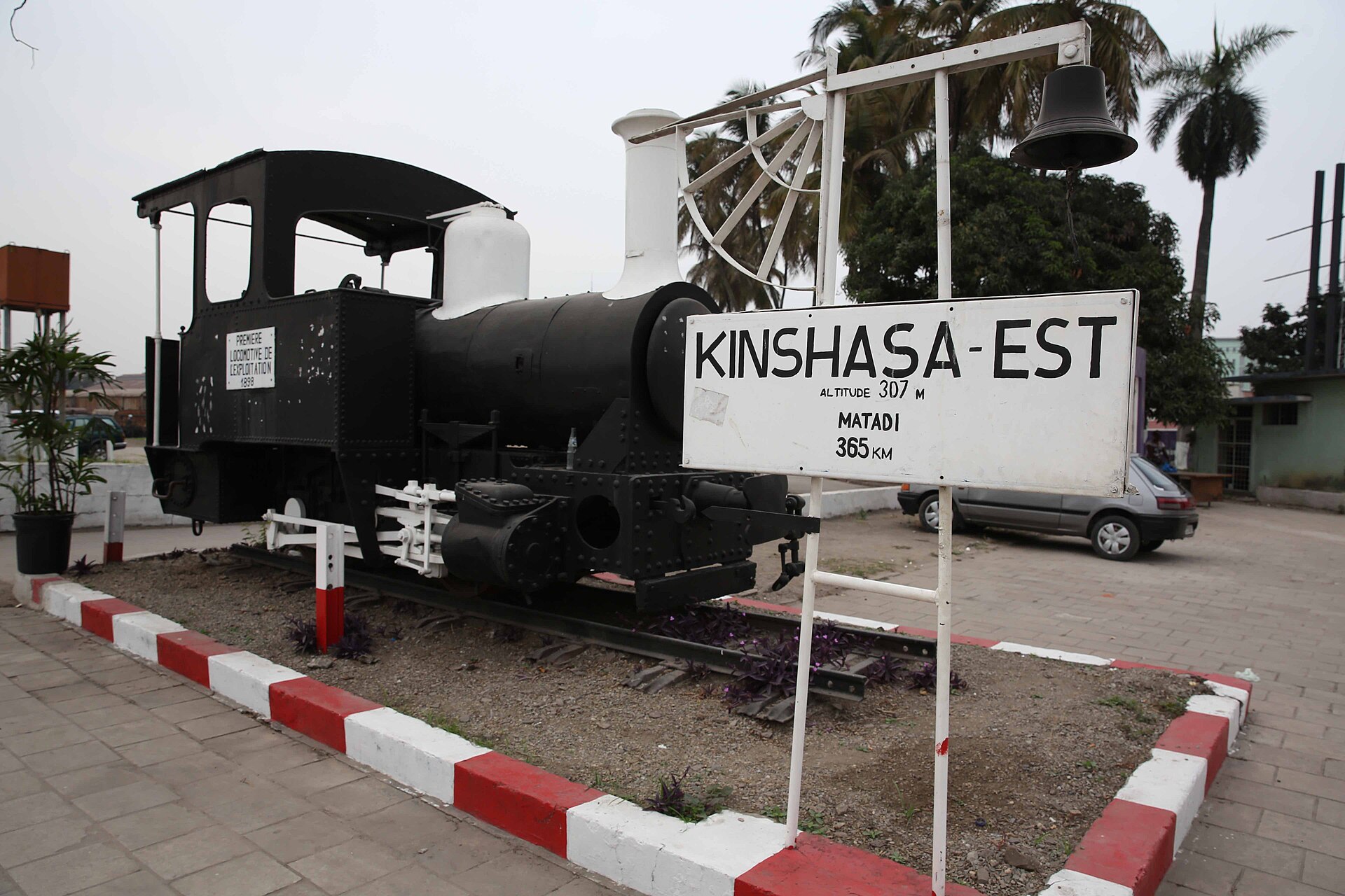 A historic steam locomotive on display beside the Kinshasa-Est station sign in Kinshasa
