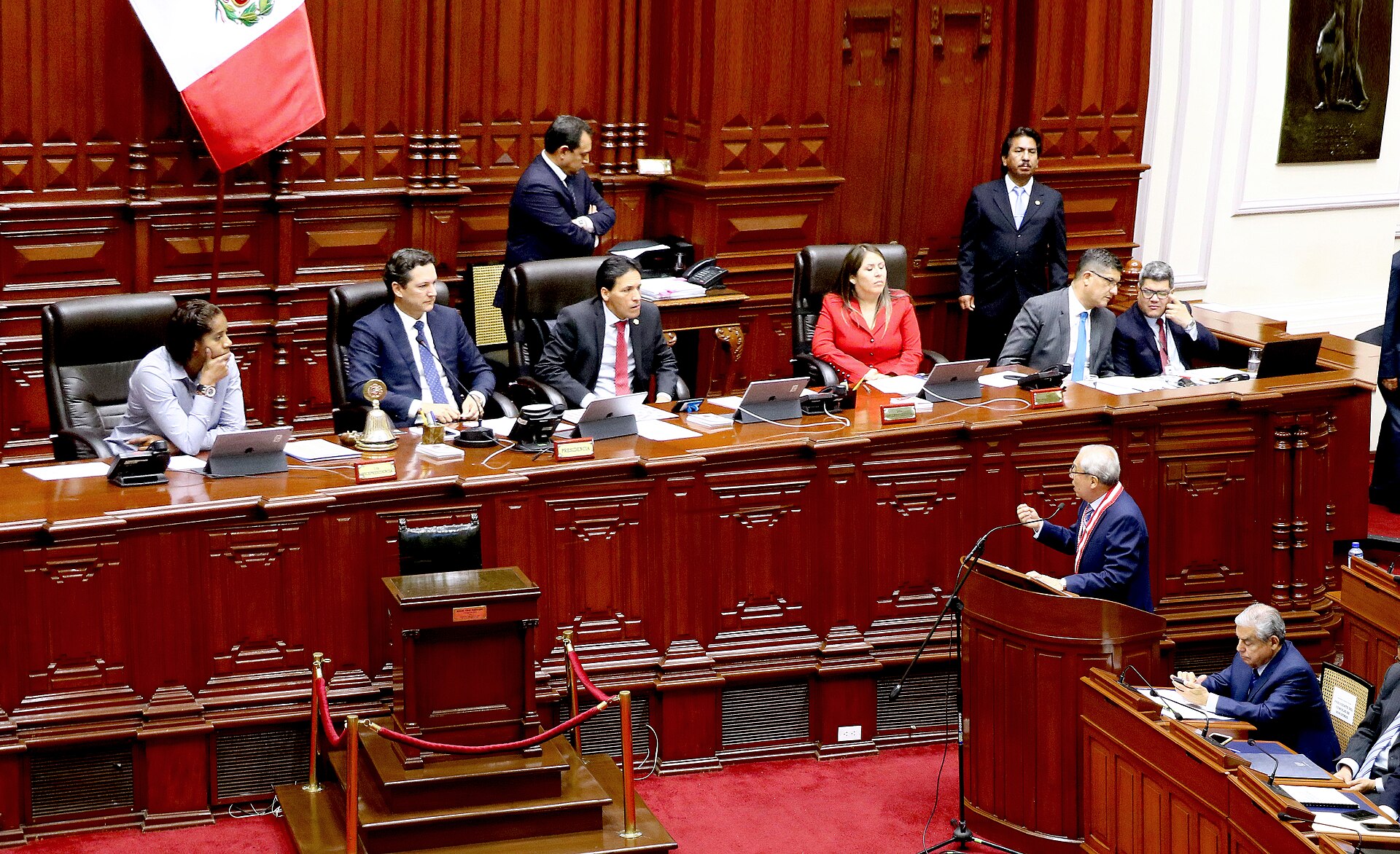Members of Peru's Congress at the presiding table under a Peruvian flag during a plenary session