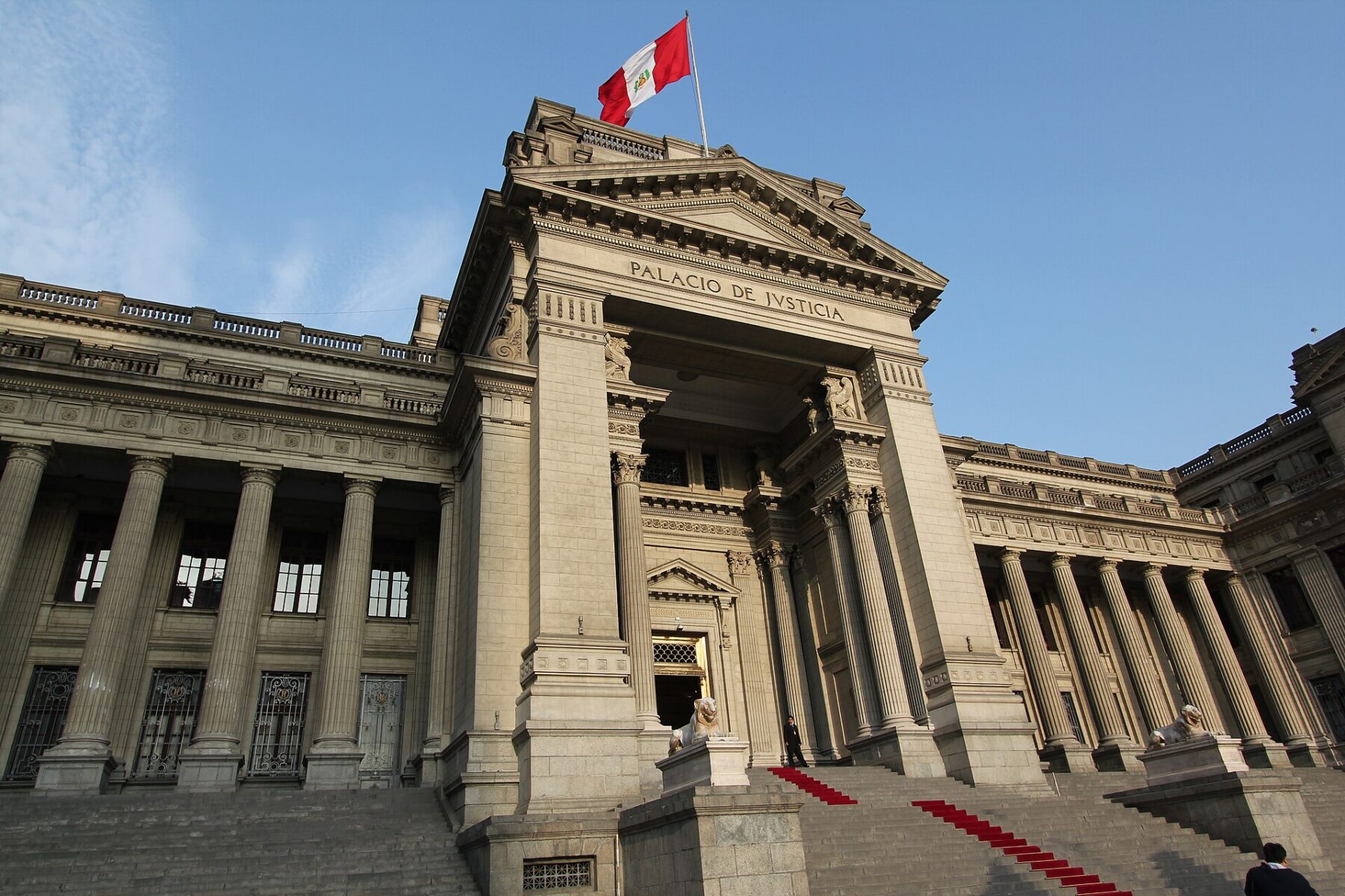 The grey stone columns and entrance of Lima's Palace of Justice with a Peruvian flag on top