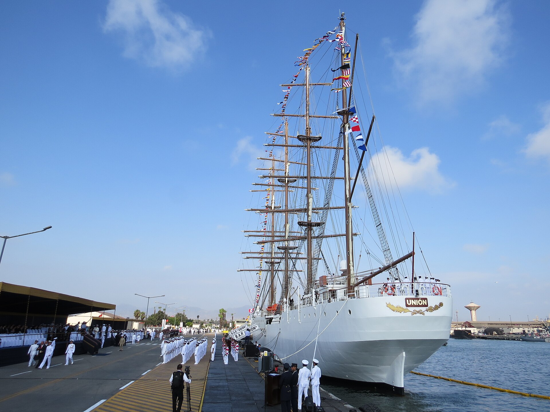 The white tall ship BAP Unión moored at a pier of the Callao Naval Base with sailors in white uniforms