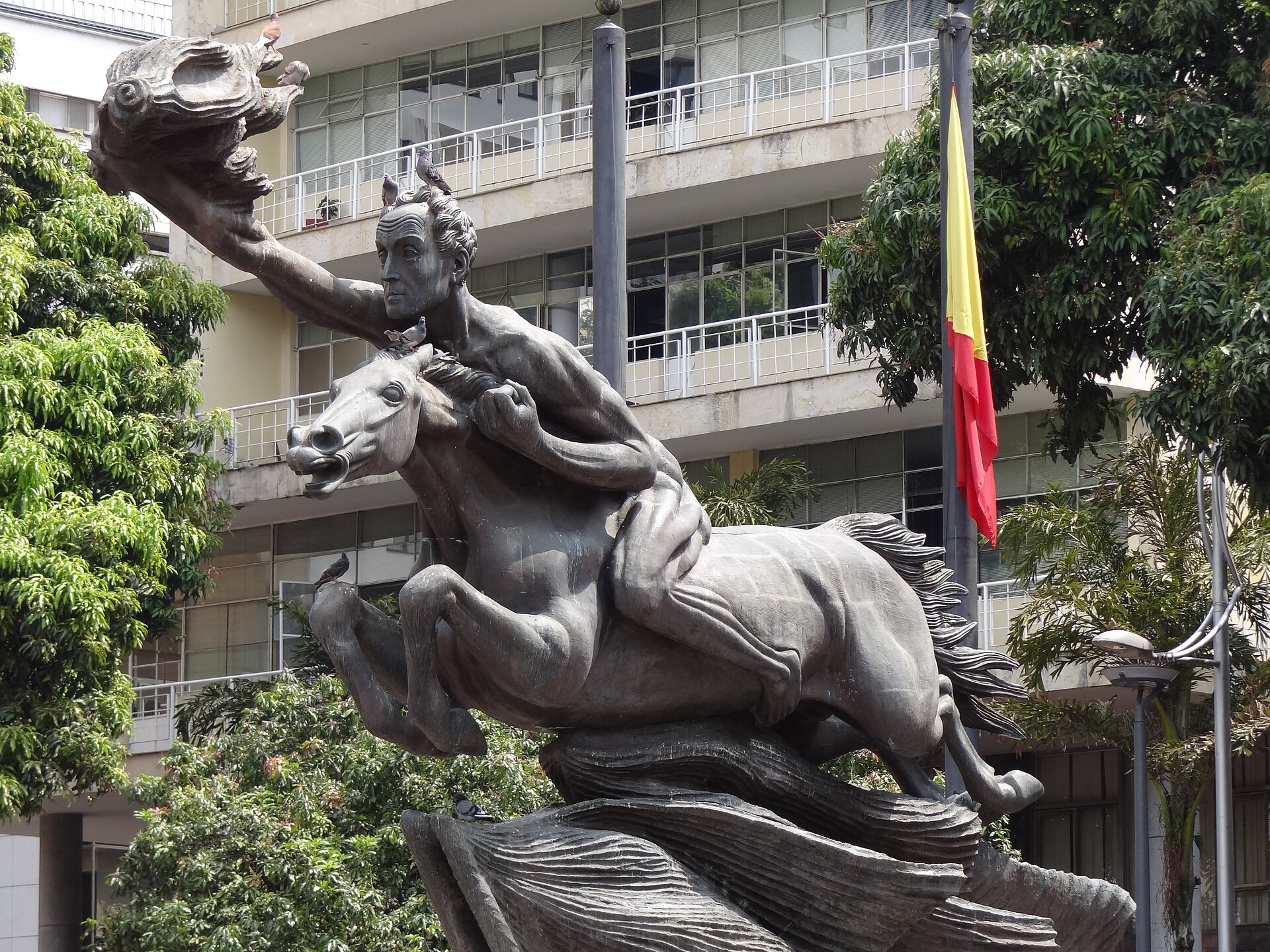 The bronze Bolívar Desnudo statue of a rider on a rearing horse in Pereira's Plaza de Bolívar, with a flag behind