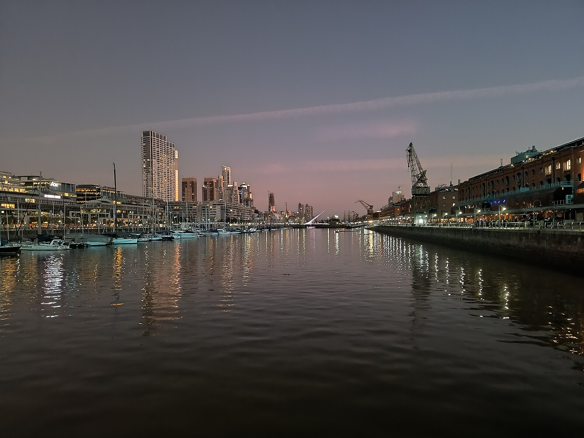 The Puerto Madero docks in Buenos Aires at dusk with high-rise towers and boats reflected in the water