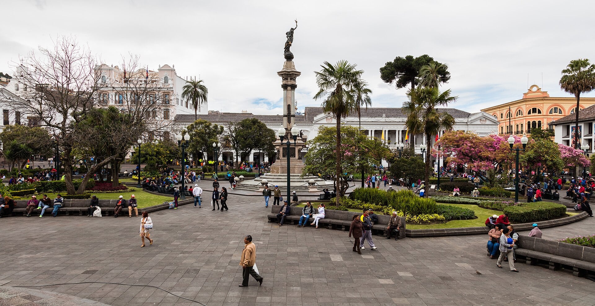 Quito's Plaza Grande with palm trees, gardens, people walking and a central monument