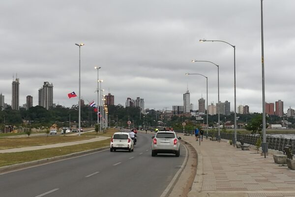 Costanera Avenue in Asunción with cars, street lamps and the city's high-rises in the distance under a grey sky