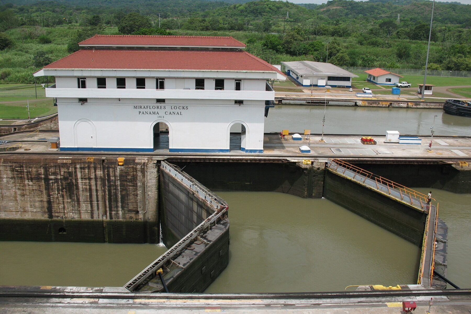 The Miraflores Locks control building with a red roof above an empty lock chamber with its double gates