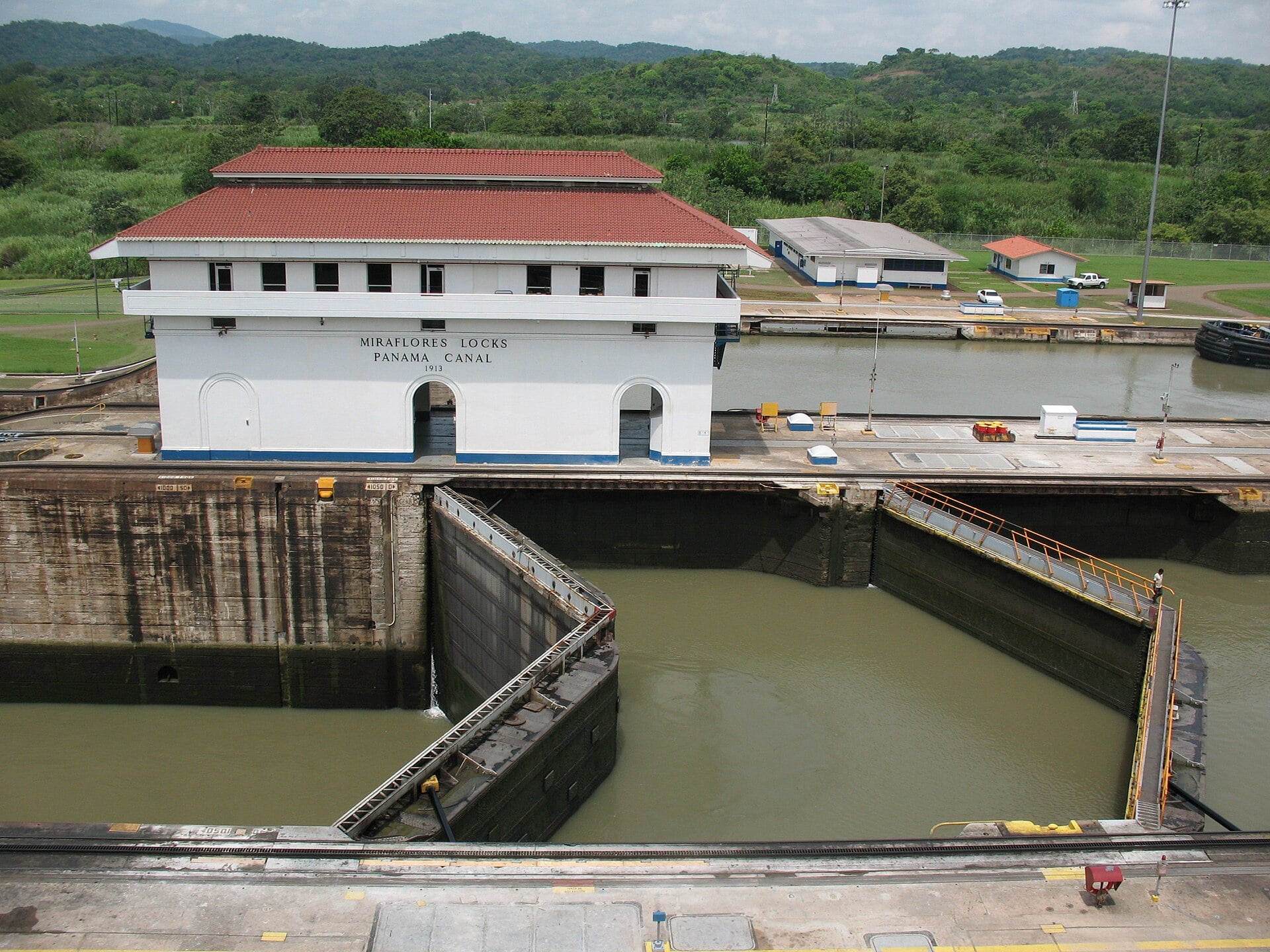 The Miraflores Locks control building with a red roof above an empty lock chamber with its double gates