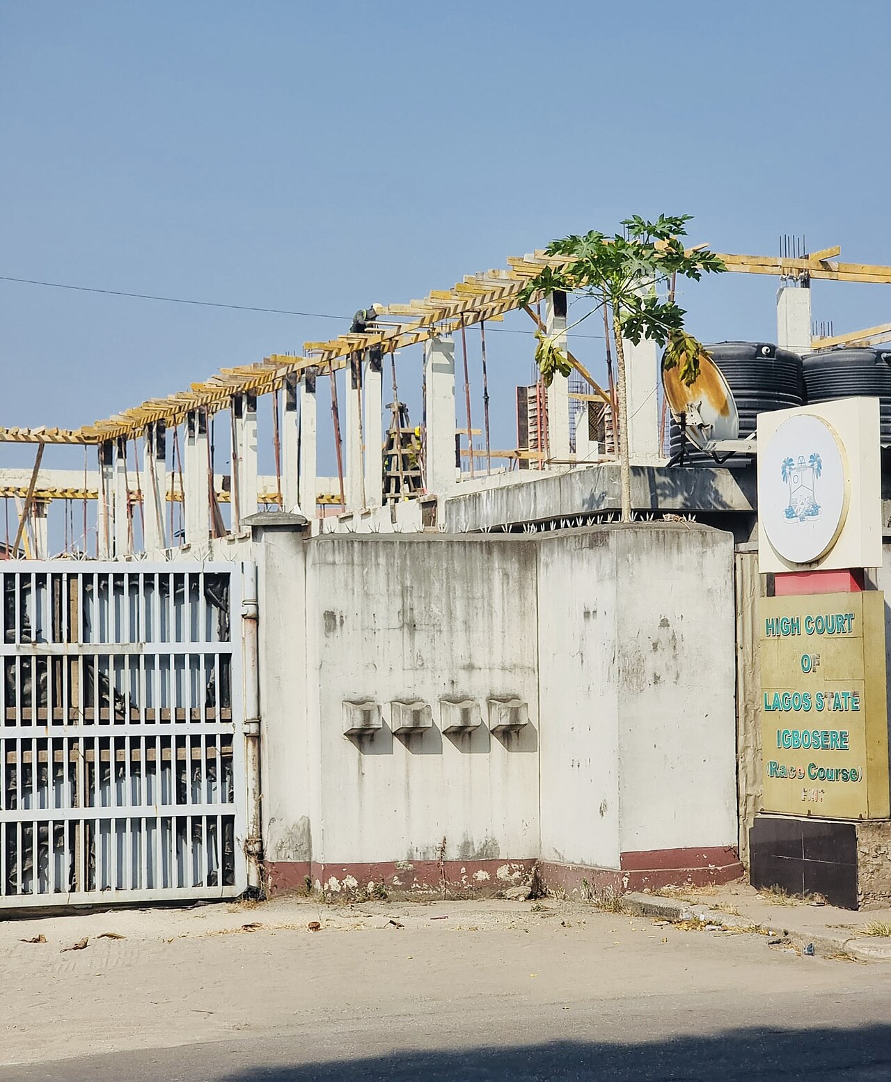 Gate and signboard of the High Court of Lagos State at Igbosere, with a building under construction behind the wall