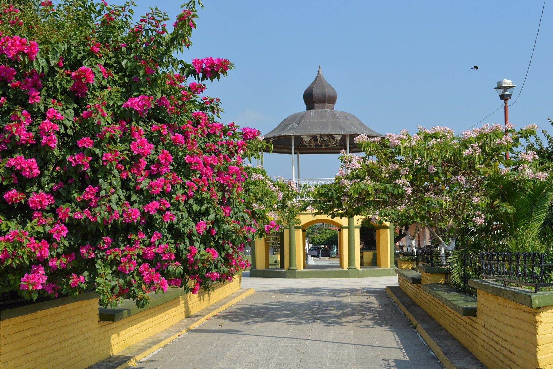 Bandstand in the main plaza of Otatitlán framed by pink bougainvillea under a blue sky