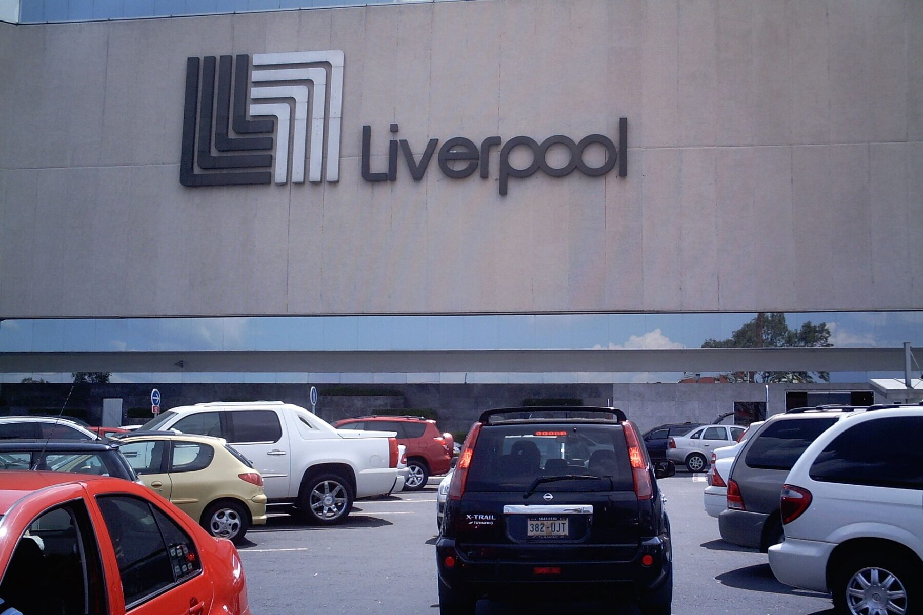 The facade of a Liverpool department store in Mexico City with the company logo above a car park with parked cars